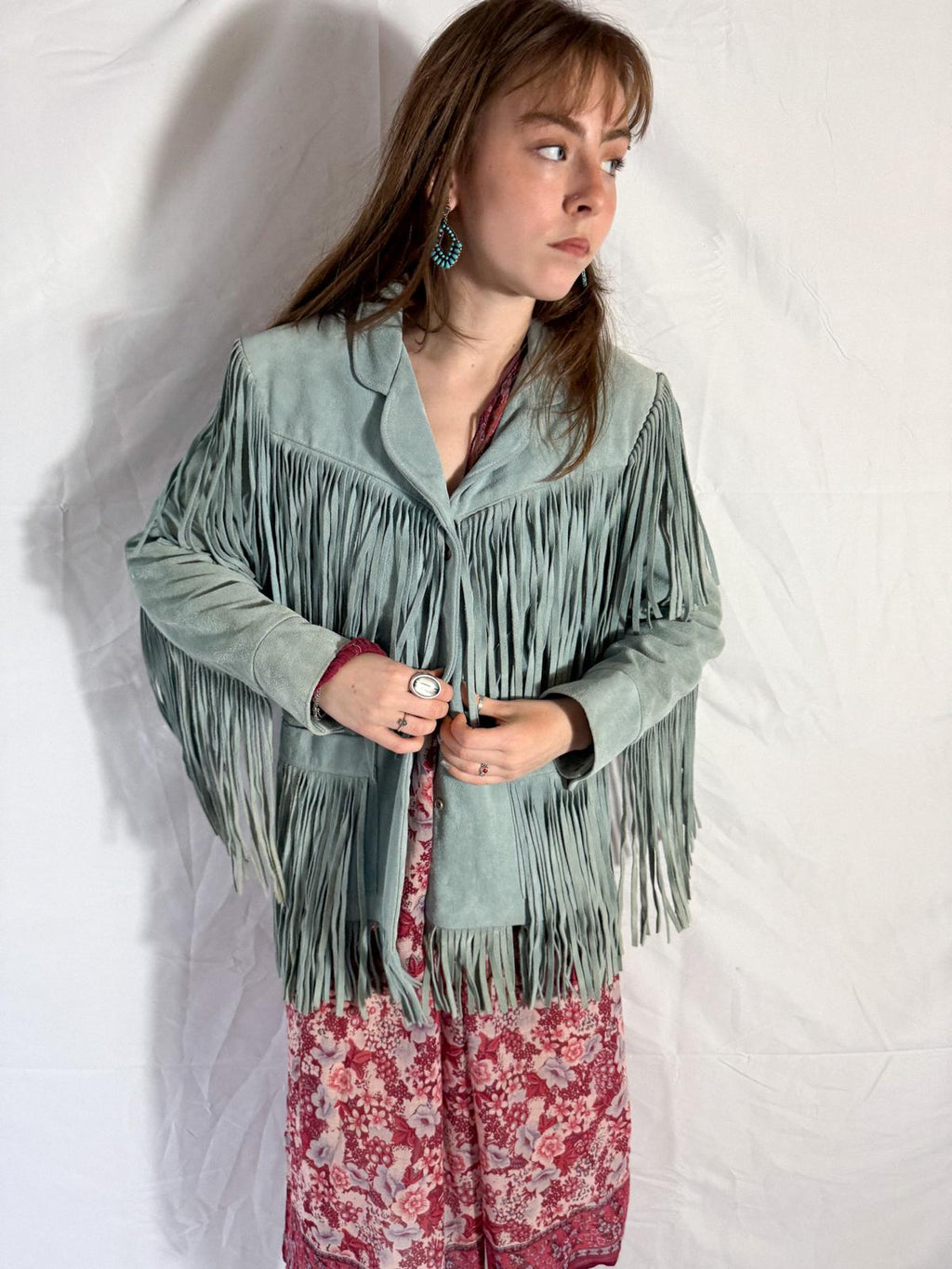 Woman wearing a green fringed jacket on a white background