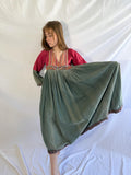Woman wearing a long, flowing dress with afghan flowy dress a white background
