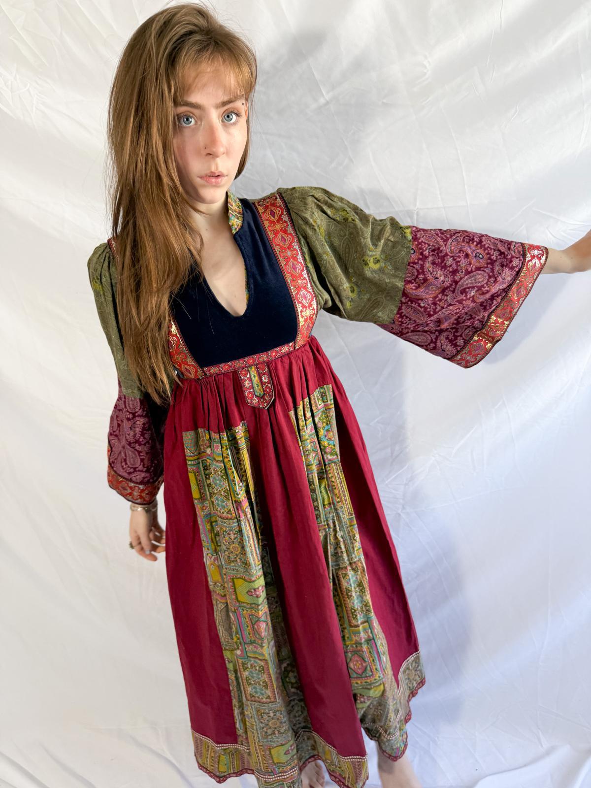 Woman wearing a colorful traditional afghan dress with a red skirt and patterned top on a white background