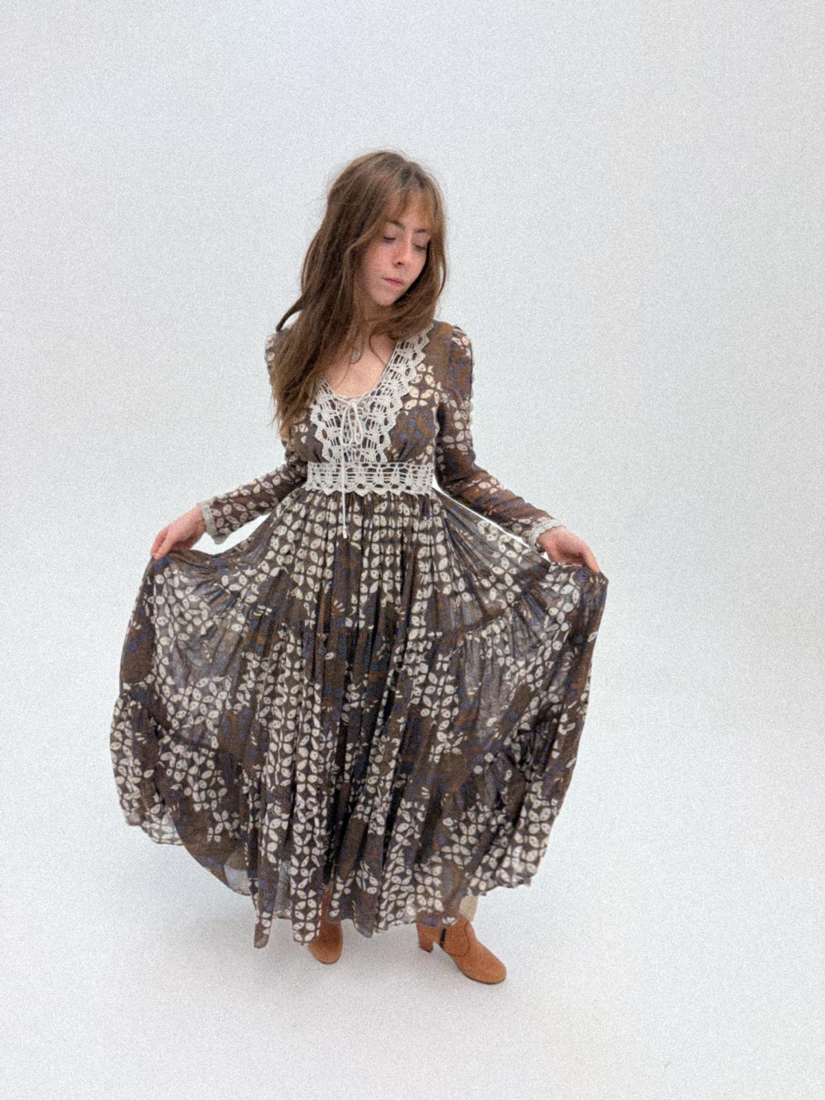 Woman wearing 1970s Gunne Sax Prairie Dress with Lace Bib and Tiered Skirt on a white background