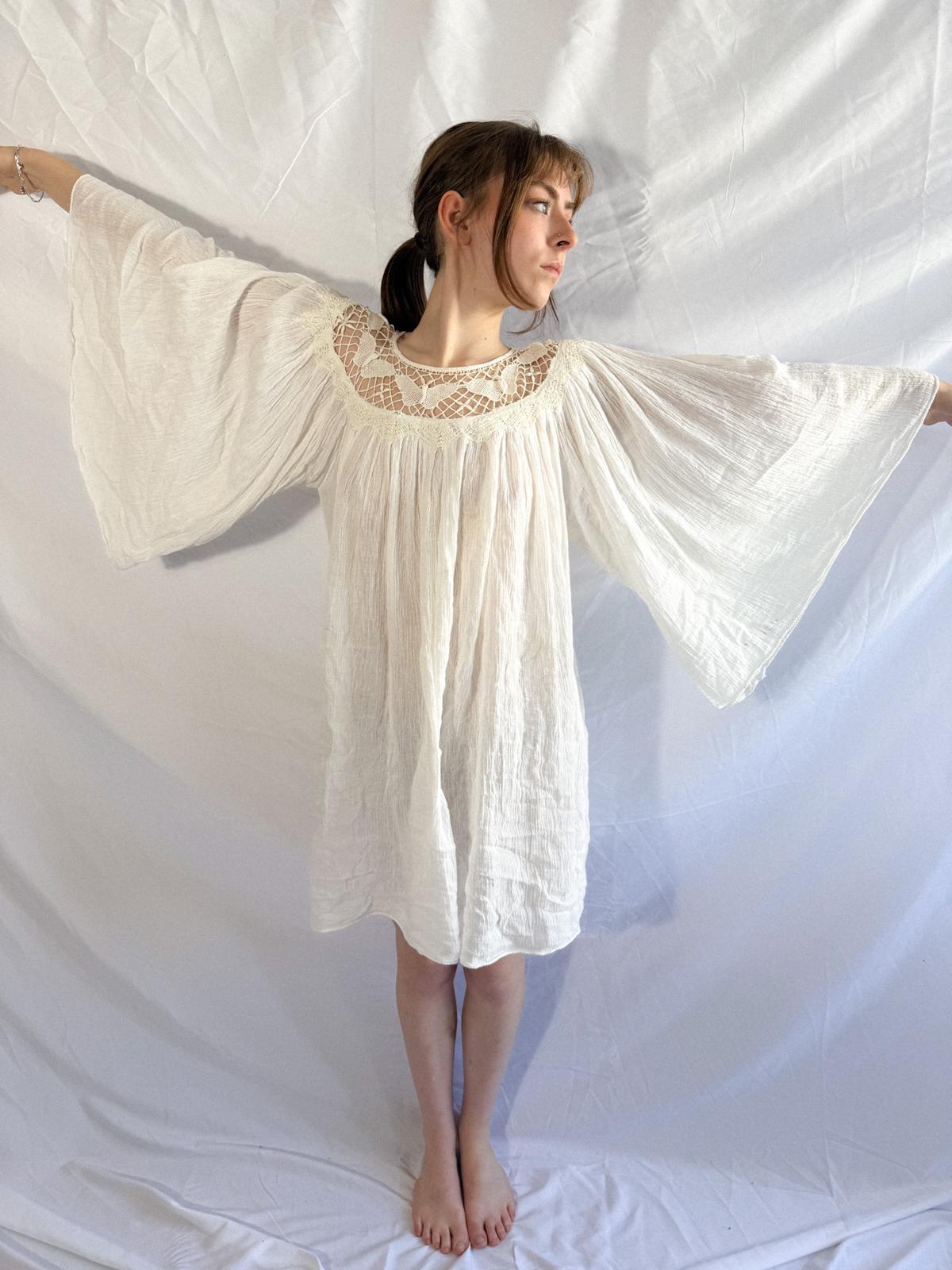 Woman wearing a white dress with lace details against a white background