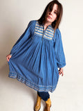 Woman wearing a blue 1970s Cotton Gauze and Lurex Dress on a plain background