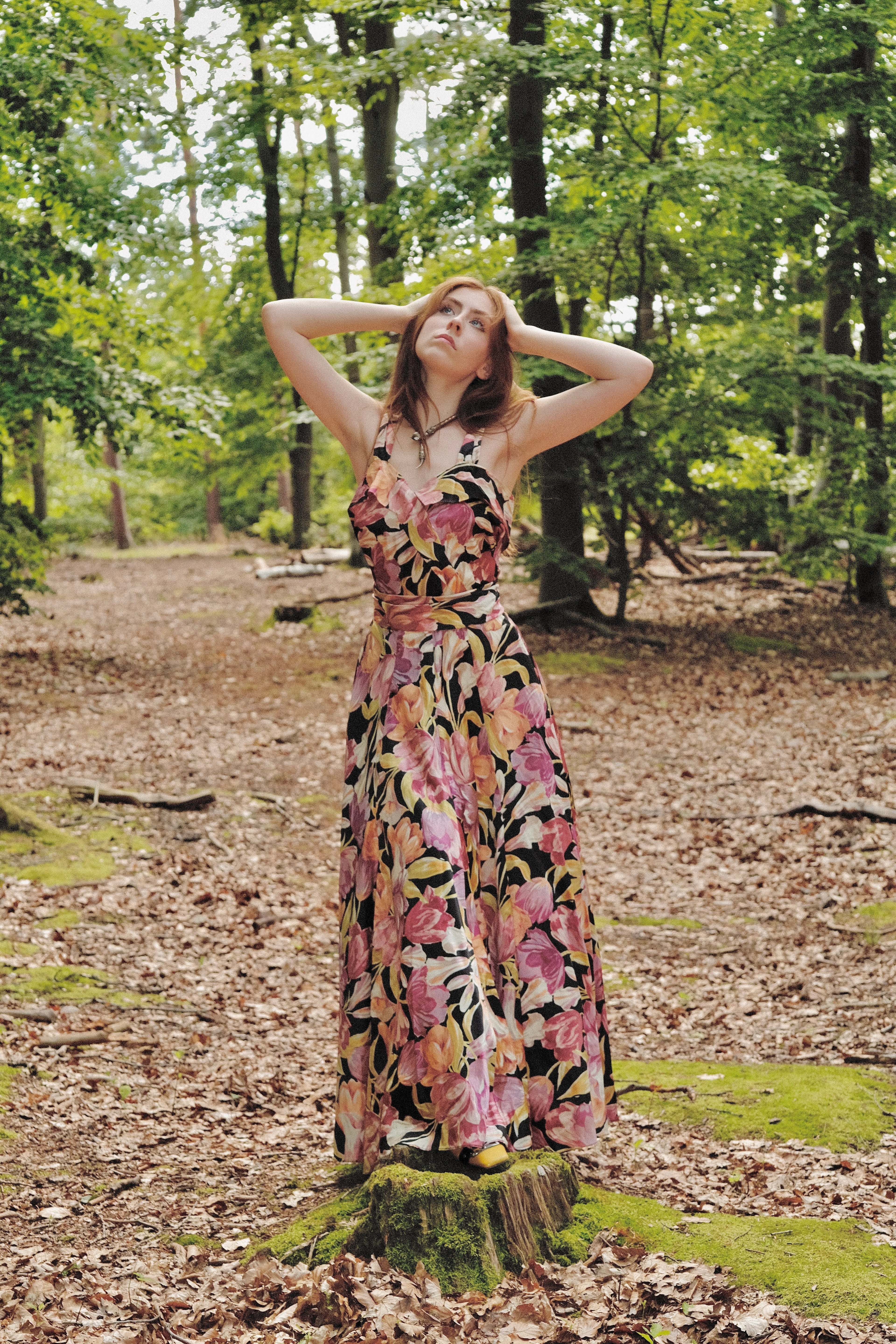 Woman in a 1930s Satin Tulip Gown standing on a forest floor with trees in the background