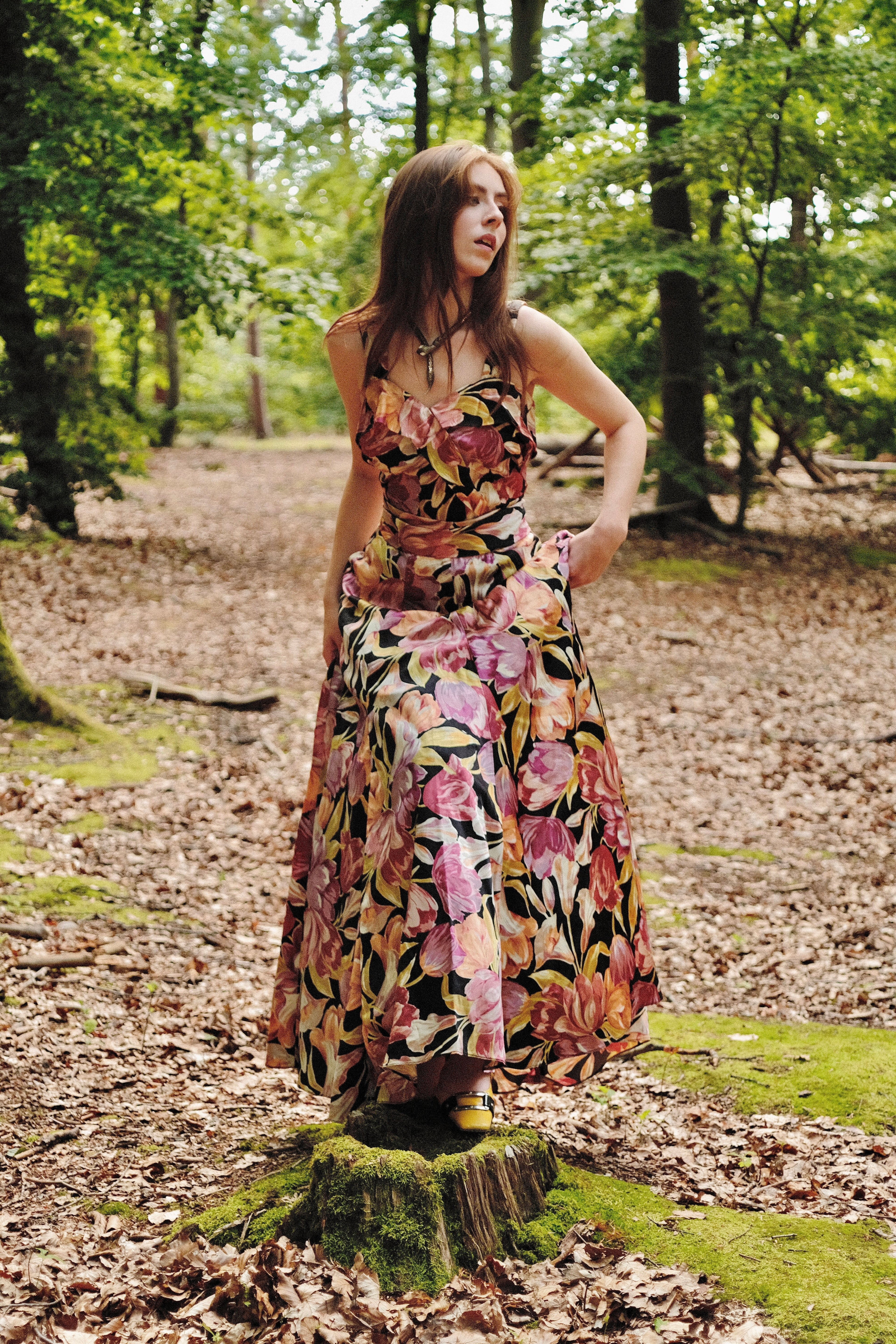 Woman in a floral dress standing in a forest