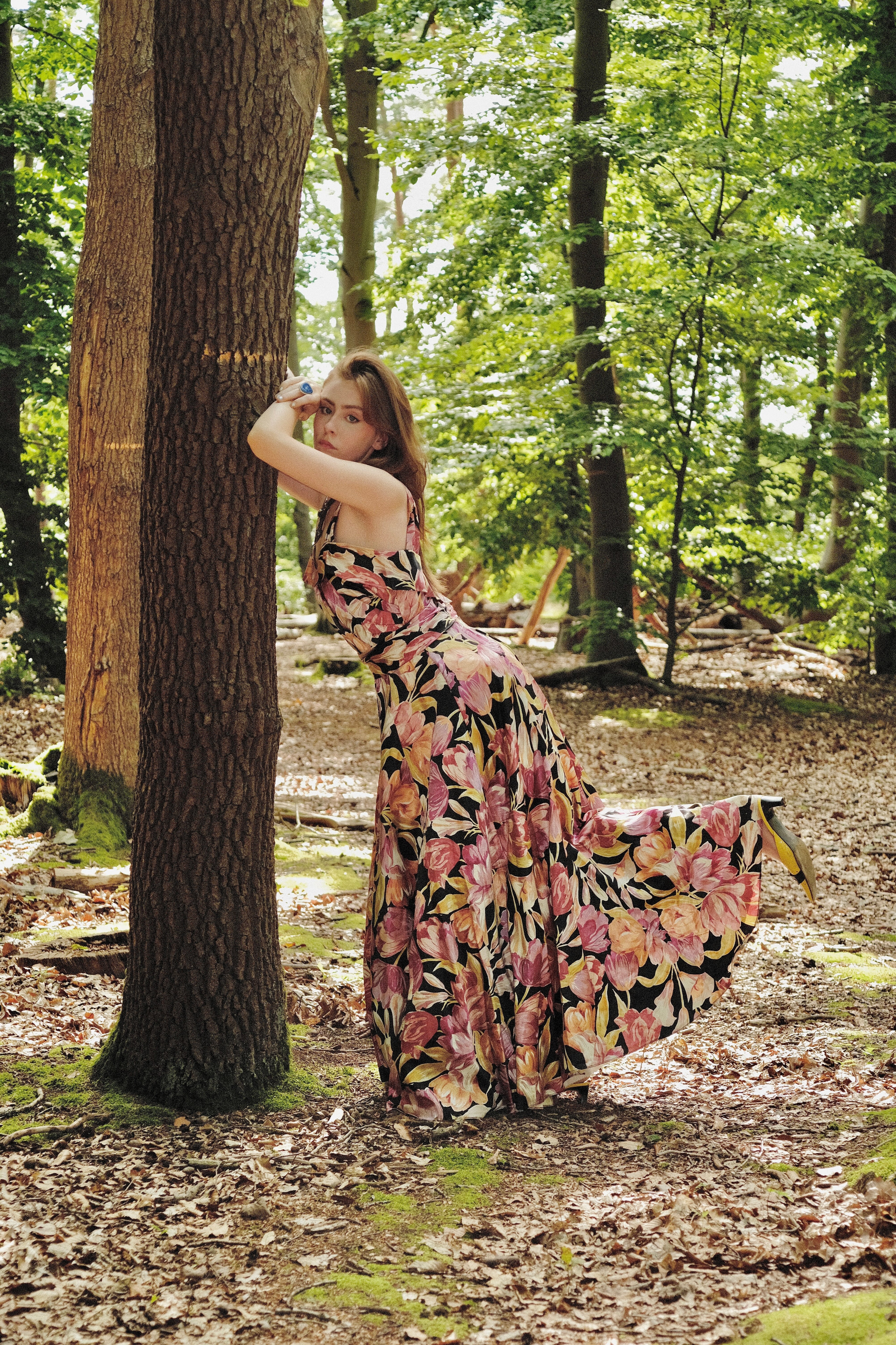 Woman in a floral dress standing in a forest