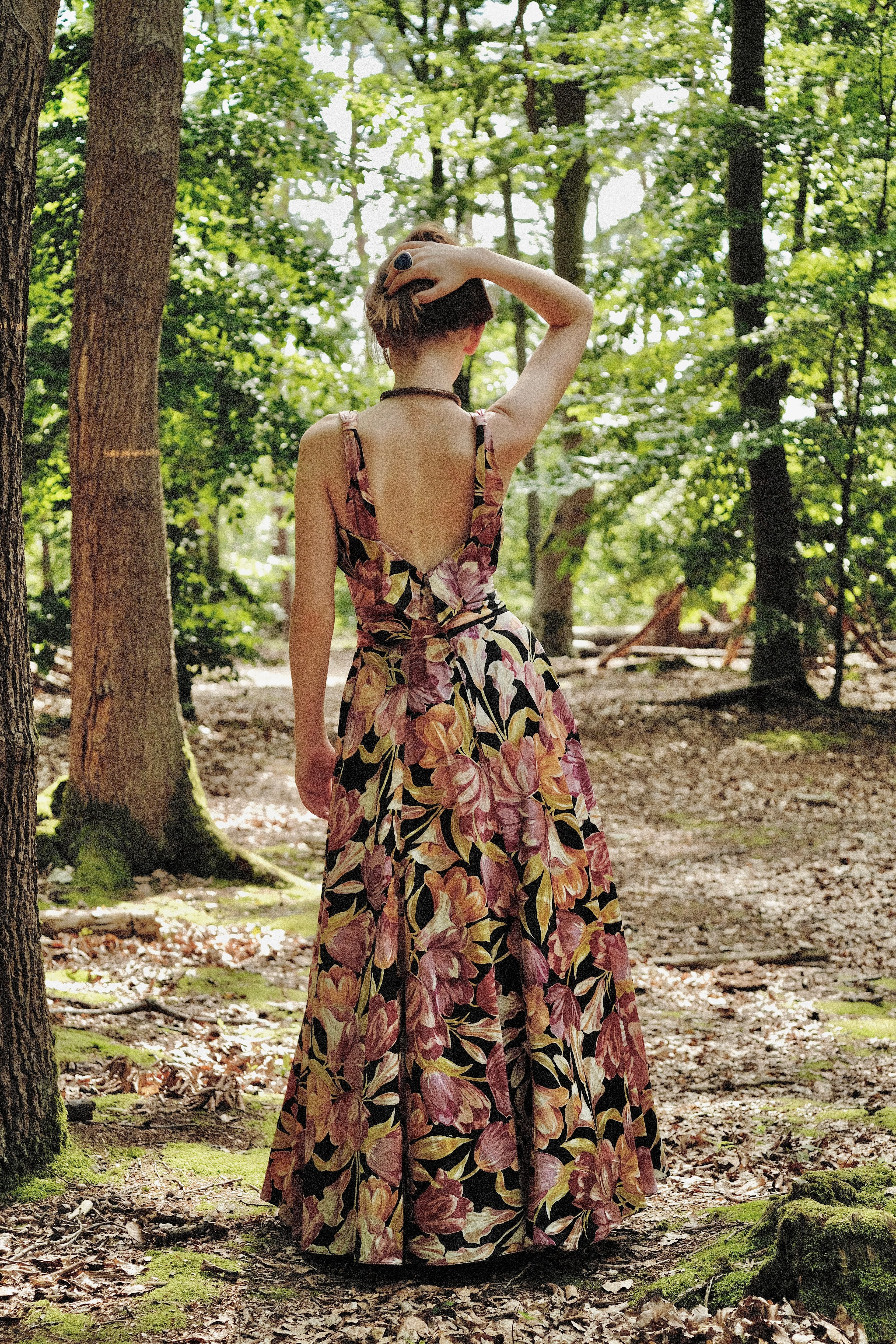 Woman in a floral dress standing in a forest
