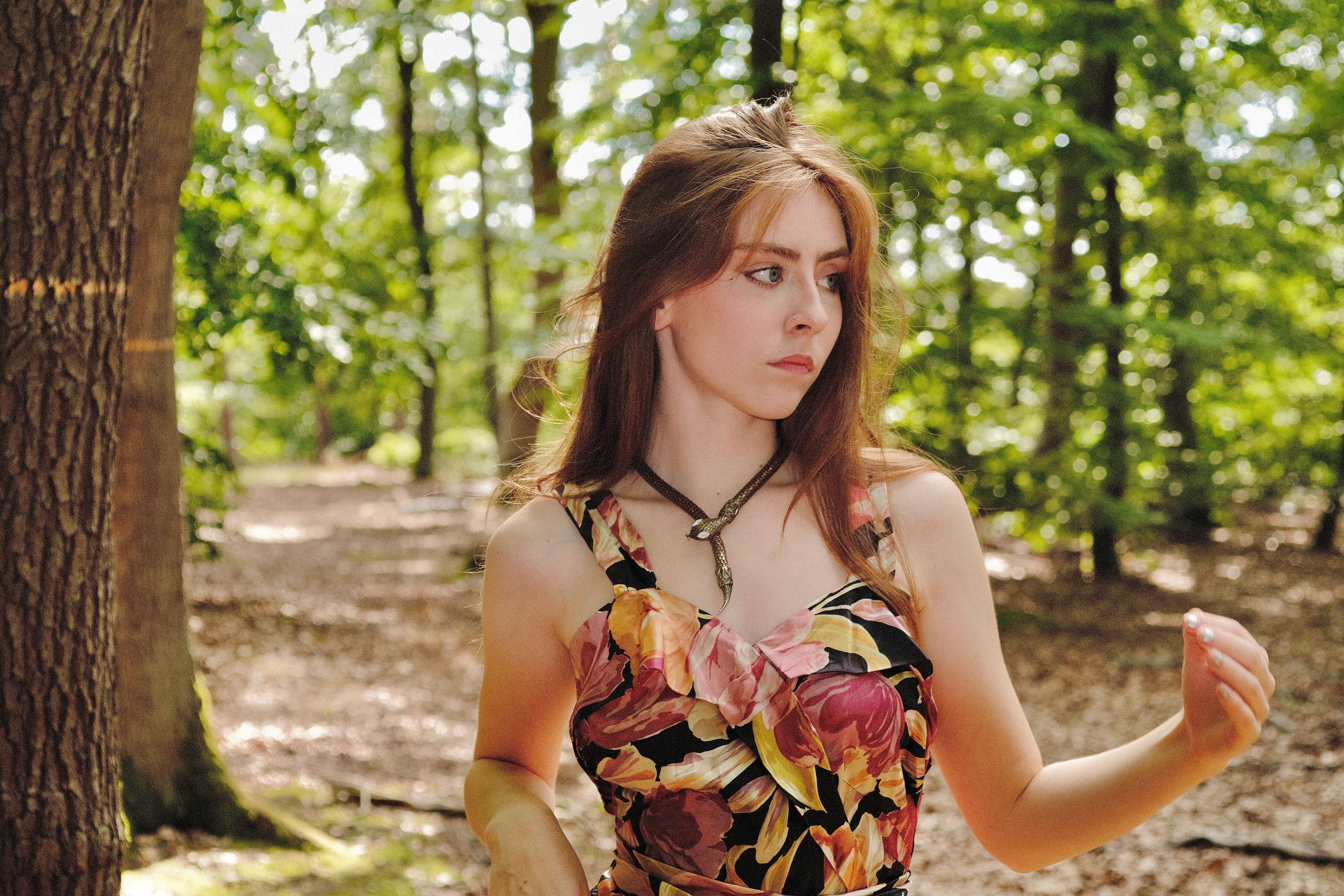 Woman in a floral dress standing in a forest