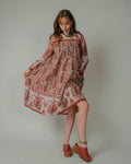 Woman wearing a 1970s Wings Rainbow Lurex Dress  and red shoes on a plain background