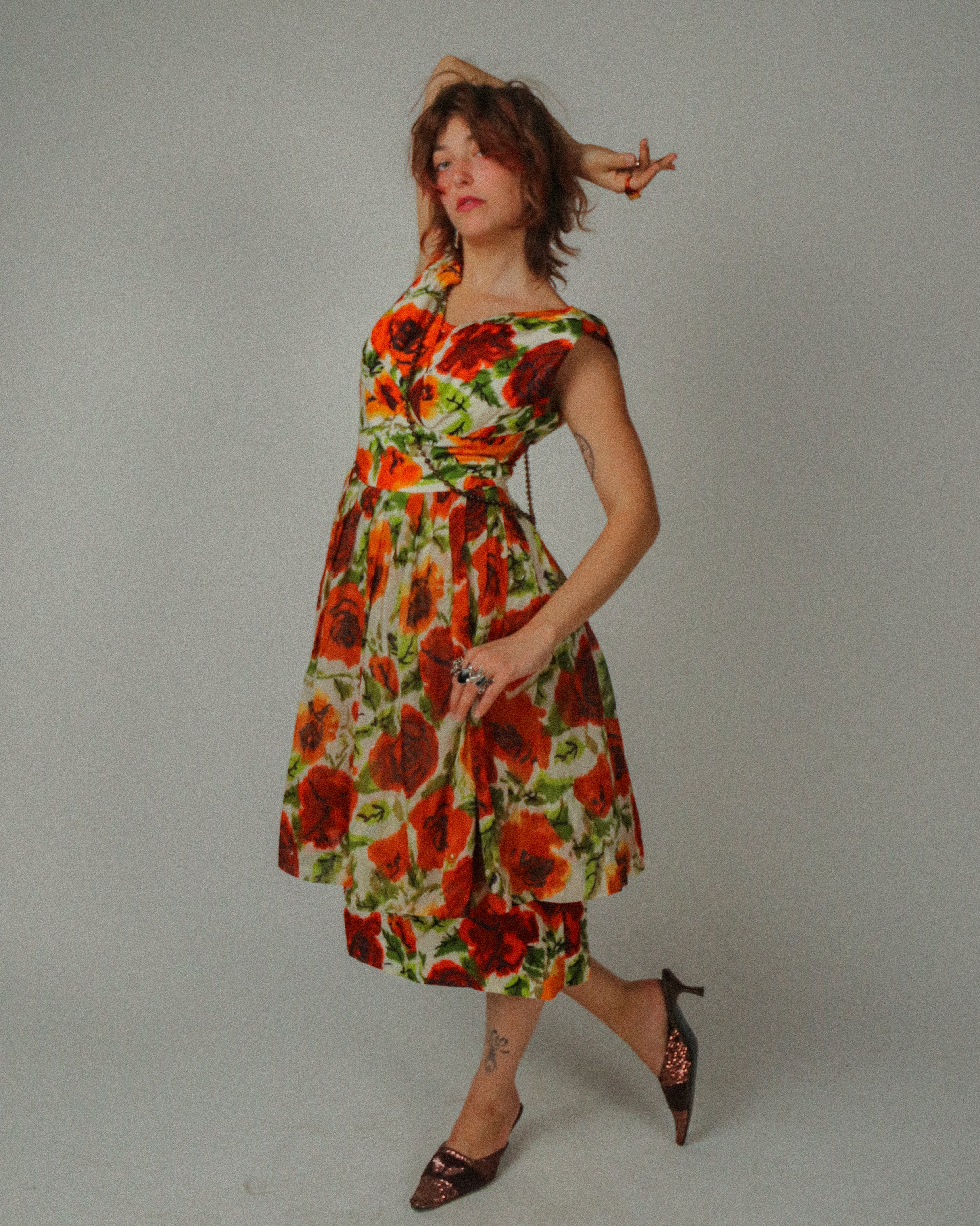 Woman wearing a colorful floral dress against a plain background