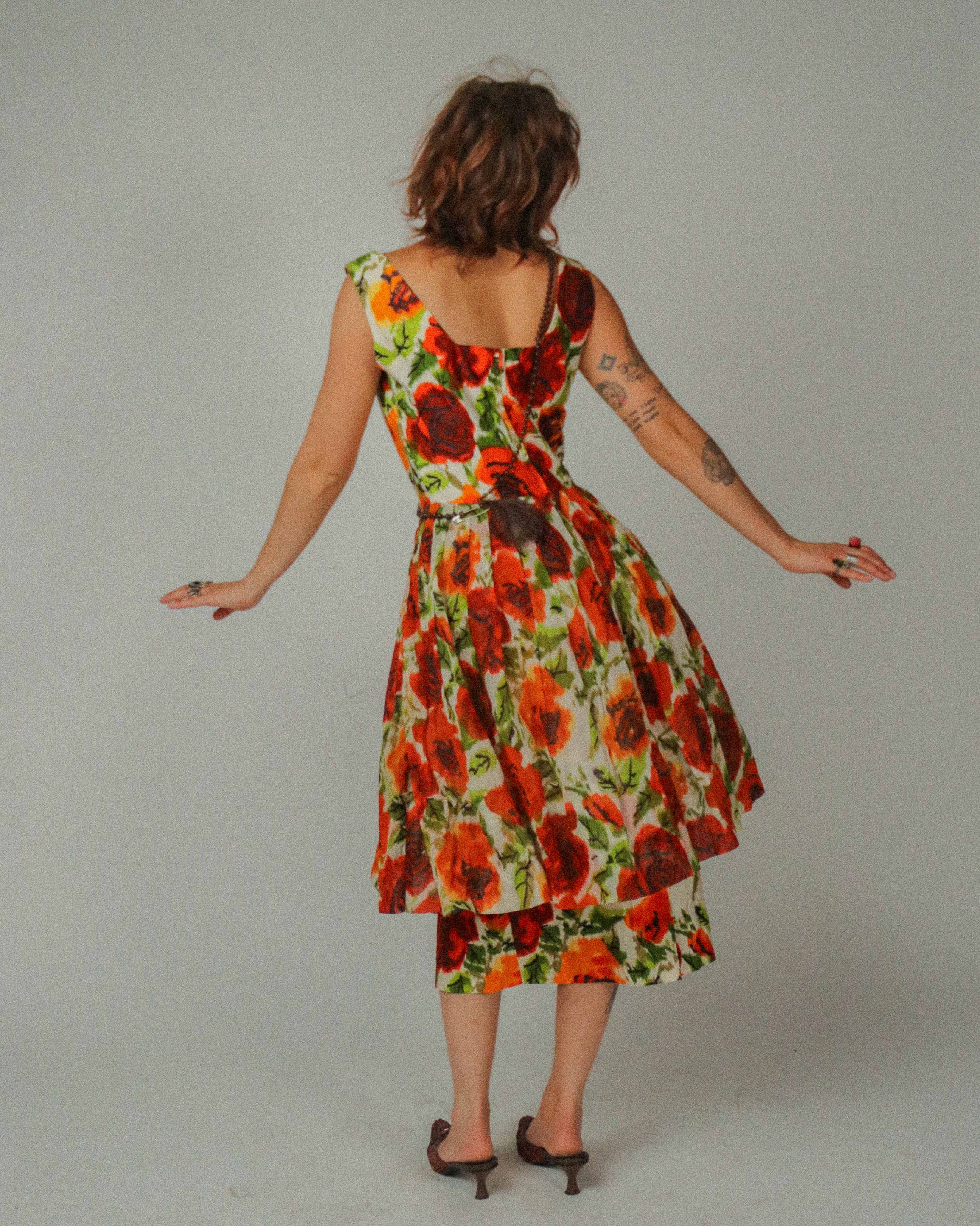 Woman wearing a floral dress with red and green pattern on a plain background