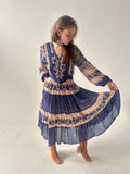 Woman wearing a blue and beige patterned dress on a plain background